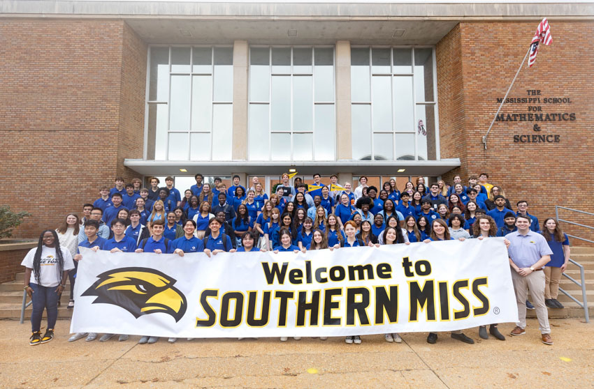 students pose in front of the school